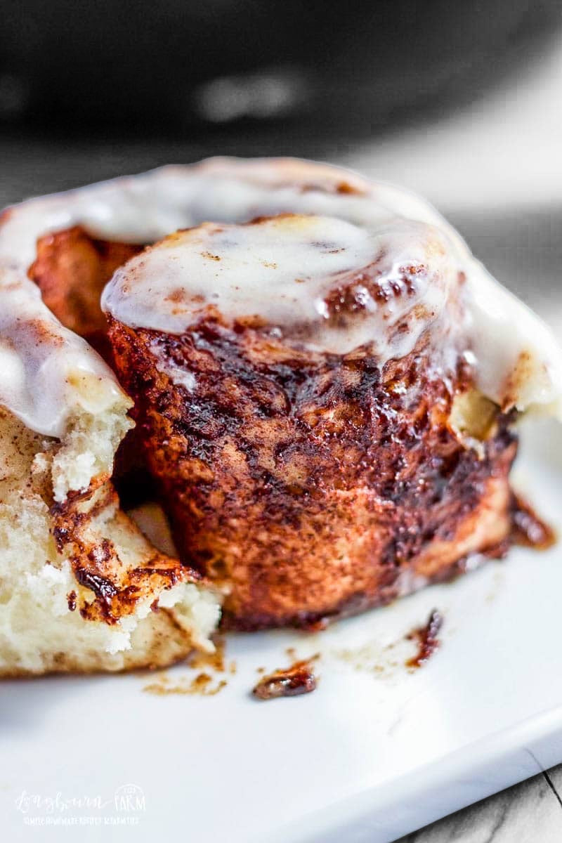 Sticky Bun cinnamon roll topped with icing on a serving plate