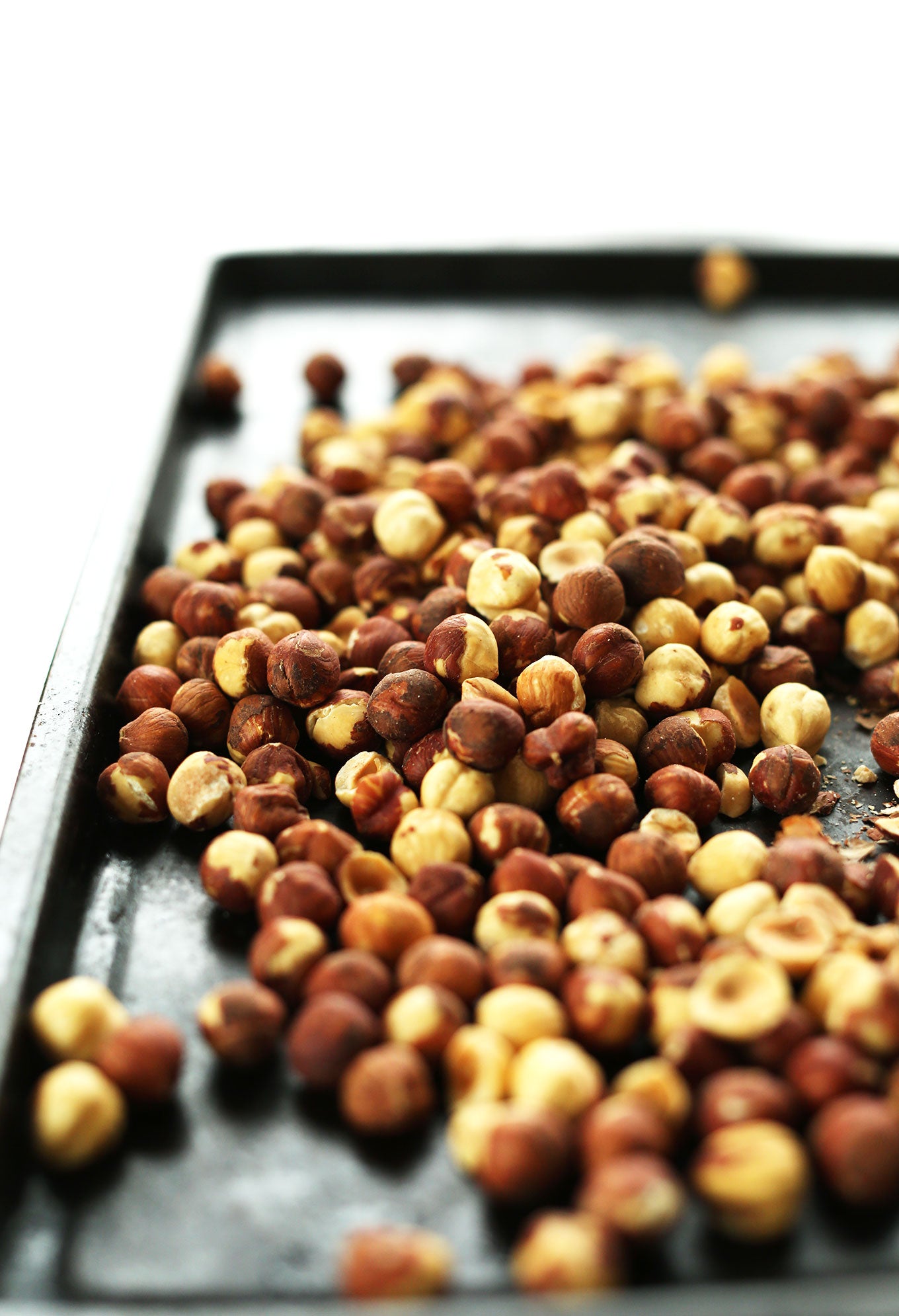 Oven-roasted hazelnuts spread out on parchment paper